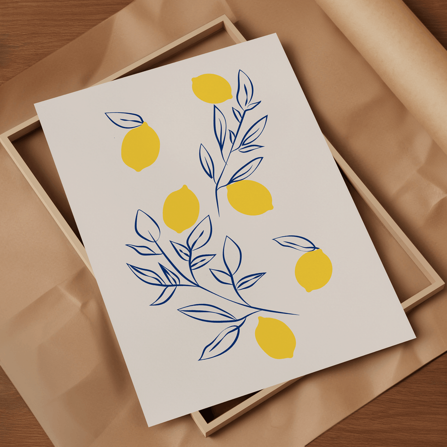 Art print of lemons in block yellow and wispy navy blue leaves and stems scattered on an off white page. The print is resting on a light wooden frame on top of brown parcel paper.