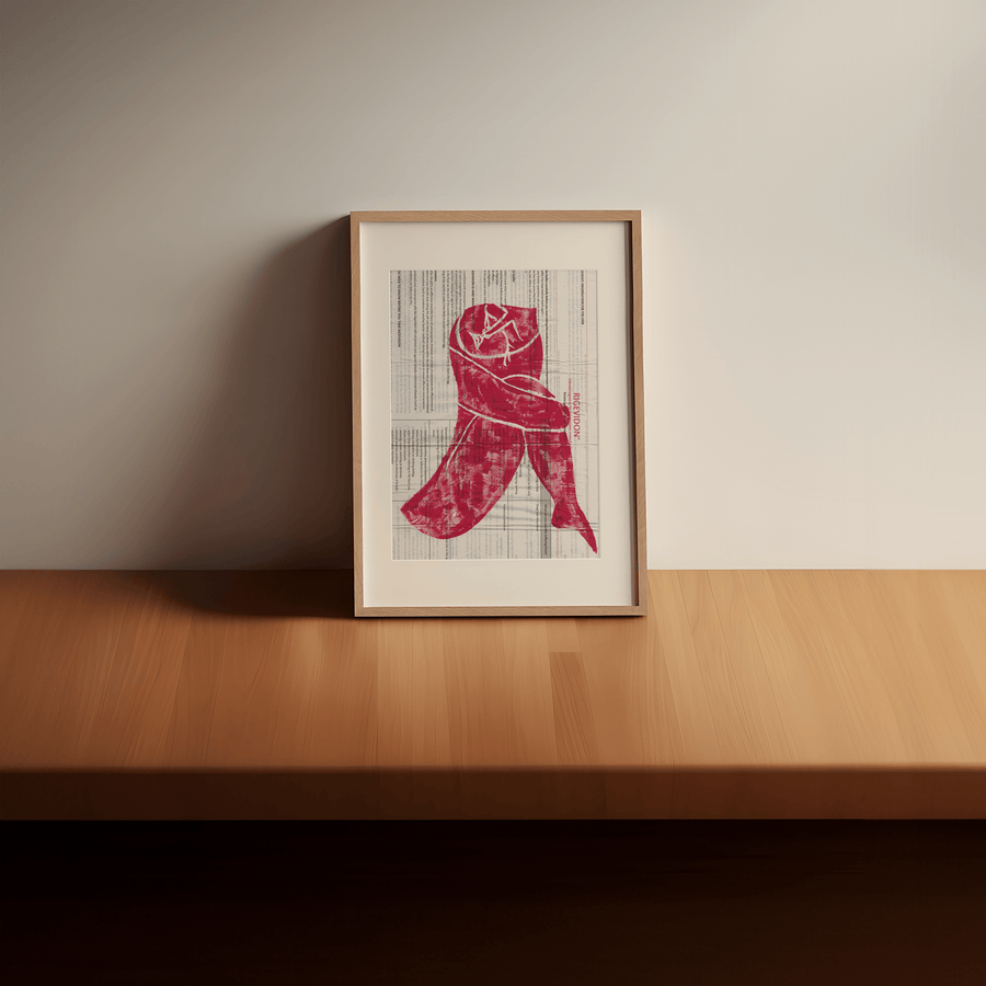 Lino print of a woman crying in red acrylic paint on a ‘Rigevidon’ contraceptive pill leaflet. Print displayed in a light wooden frame with a cream window mount, rested on a wooden table, leaning against a cream wall.