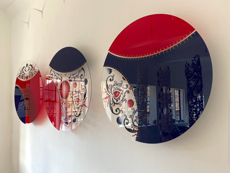 3 circular textile artworks by Jennifa Chowdhury made of acrylic and gold thread, each split into 3 sections of red, navy and transparent patterned section.