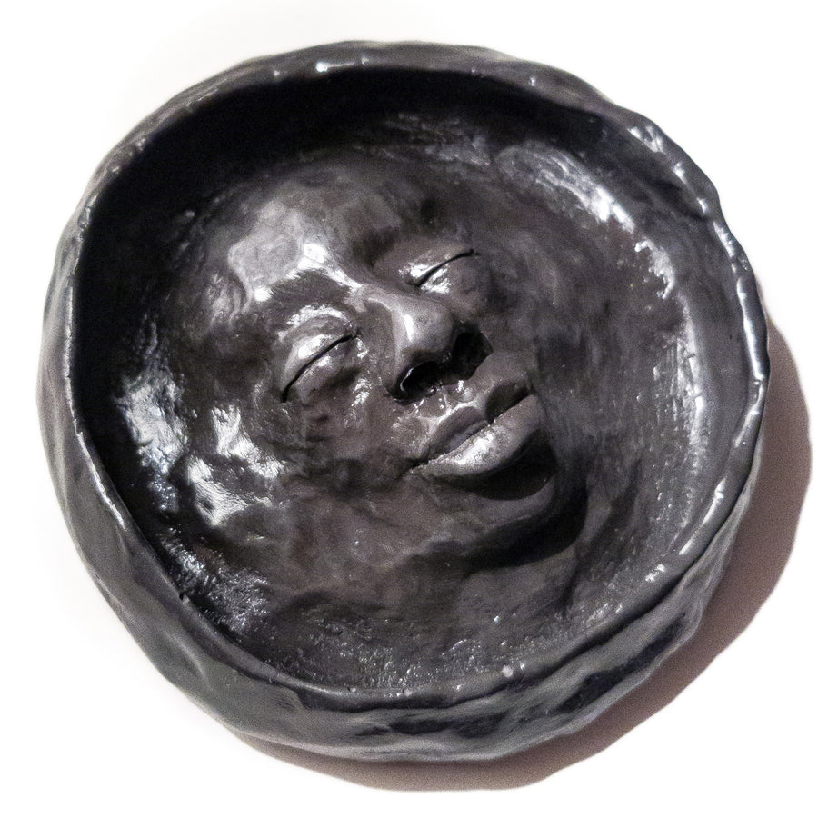 High gloss coated black trinket bowl with a feminine face sculpted into the centre.