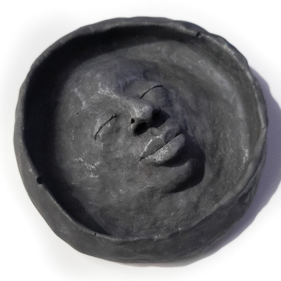 Matte black trinket bowl with a feminine face sculpted into the centre.