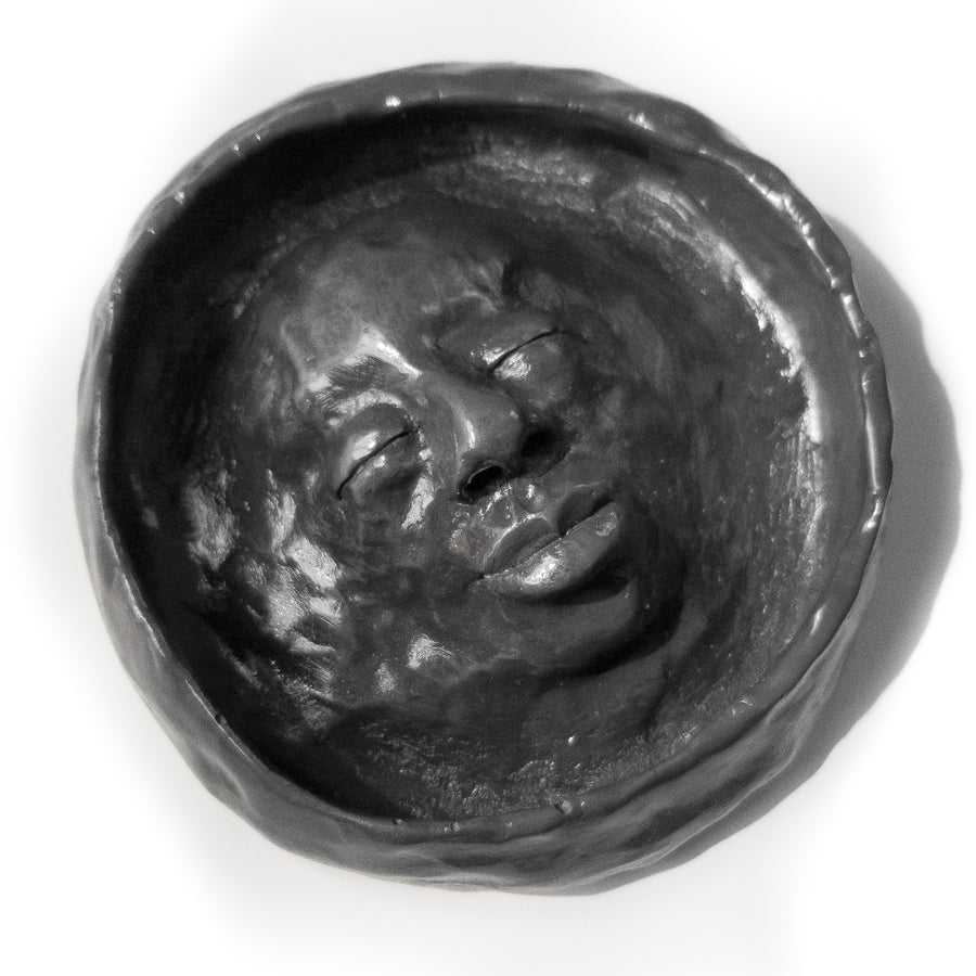 Semi-matte black trinket bowl with a feminine face sculpted into the centre.